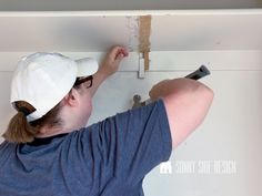 a woman is working on the ceiling in her home with screwdrivers and paint rollers