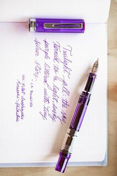 a purple pen sitting on top of an open notebook next to it's writing