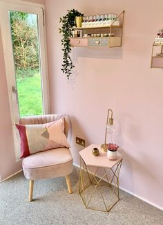 a pink room with a chair, table and shelves