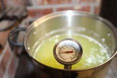 a large metal pot filled with liquid and a thermometer on it's side