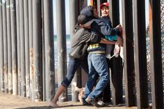 two people hugging each other near a fence