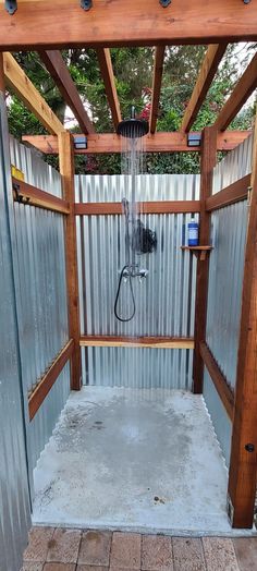 an outdoor shower is shown in the middle of a patio with wood and metal walls