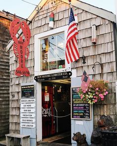 an old wooden building with signs and flags on the front door that read, new world lobster co