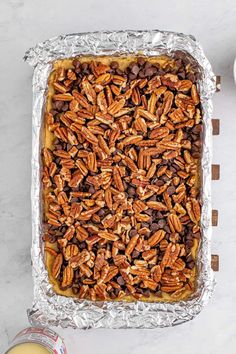 pecans and chocolate in a baking dish on top of tin foil next to a can of milk