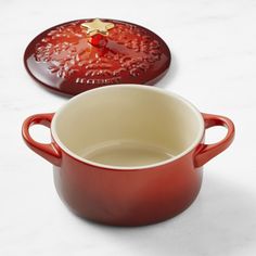 a red pot with a lid sitting on top of a white counter next to another bowl