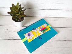 a notepad and pen sitting next to a potted plant