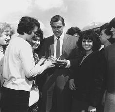 a group of people standing around each other and looking at something on a cell phone