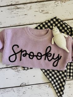 a pink sweater with the word spooky written on it and a stuffed animal