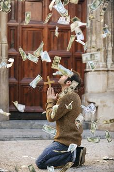 a man sitting on the ground with money falling from his hands in front of him