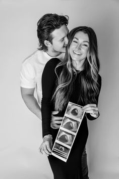 a man and woman kissing each other while holding an object in front of their face