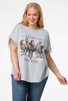 a woman standing in front of a white background wearing jeans and a t - shirt with horses on it