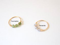 two gold rings with different colored beads on them and the words tourmaline, tanzanine