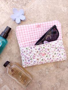 an open purse sitting on top of a table next to a bottle of perfume and sunglasses