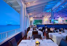 an empty restaurant with tables and chairs overlooking the ocean