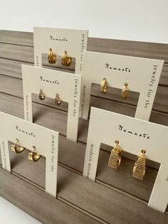 four pairs of earrings are on display in front of the price card for each pair