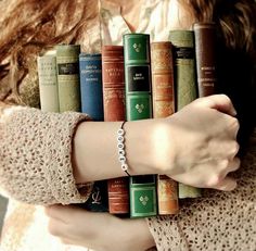 a woman holding a stack of books in her hands with the words book written on them