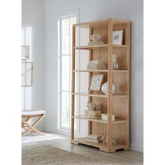 a wooden bookcase with books on it in a living room next to a window