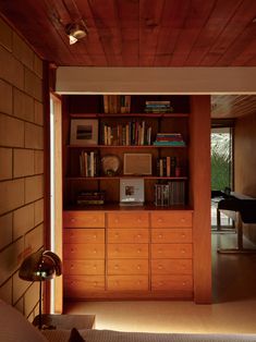 an open bookcase in the corner of a room with a piano and bookshelf