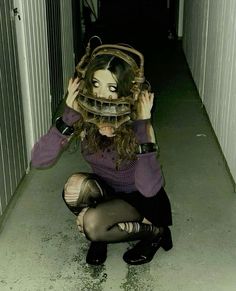 a woman kneeling down with her head in a cage over her face and hands behind her head