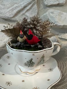 a teacup filled with christmas decorations on top of a saucer