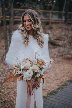 a woman wearing a white fur coat holding a bouquet