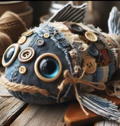 a stuffed fish made out of old jeans and buttons on a wooden table with yarn