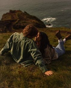 a man and woman laying on the ground next to each other in front of an ocean