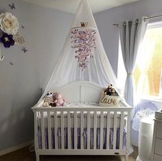 a baby's room decorated in purple and white with flowers on the wall, crib