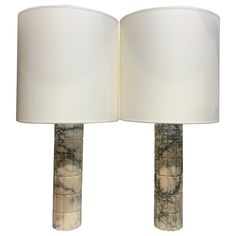 two marble lamps with white shades on them