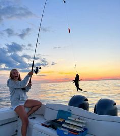 a woman sitting on the back of a boat while holding onto a fishing rod