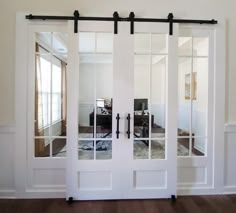 an open white door with mirrored glass and black hardware on the doors side by side