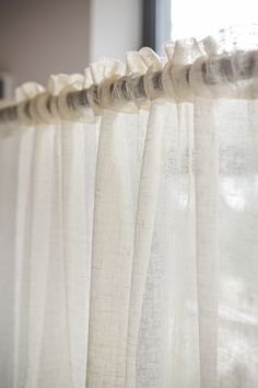 the curtains are hanging in front of the window sill, and they have ruffled edges