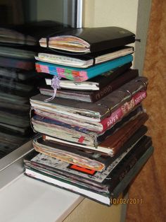 a stack of books sitting on top of a window sill