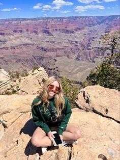 a woman sitting on the edge of a cliff