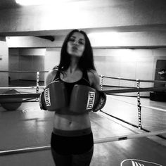 a woman standing in a boxing ring with her hands on her hips and wearing gloves