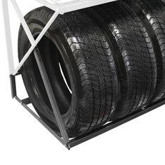 four black tires are stacked on top of each other in a metal rack that holds them