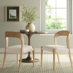 two chairs sitting at a table in front of a window with a potted plant on it