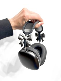 a person holding two black bells with bows on them and one bell has a bow