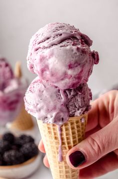 a hand holding an ice cream cone filled with blueberries