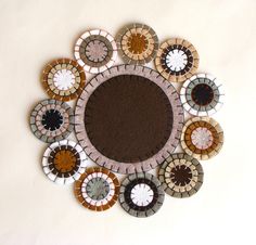 a circular mirror made out of different colored glass and stone tiles on a white wall