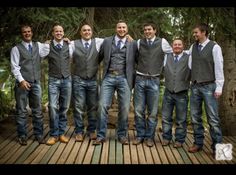 a group of men standing next to each other on a wooden platform in front of trees