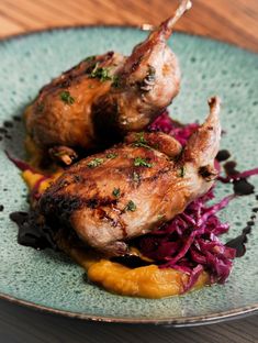 two pieces of chicken are on a plate with red cabbage and mango slivers