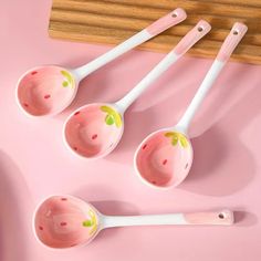 four pink and white measuring spoons on a pink surface