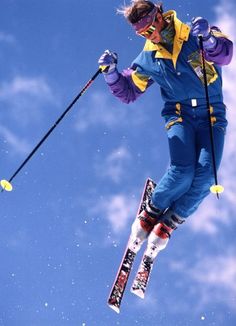 a person on skis jumping in the air with their arms extended and feet apart