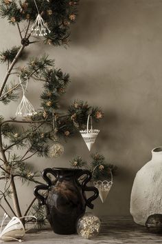 a vase sitting next to a pine tree with ornaments hanging from it's branches