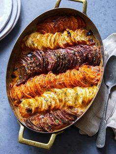 a pan filled with different types of food on top of a blue tablecloth next to silverware