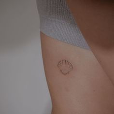 a woman's stomach with a small shell tattoo on it