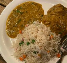 a white plate topped with rice and meat covered in gravy on top of a wooden table