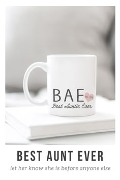 a white coffee mug sitting on top of a book with the words best aunt ever