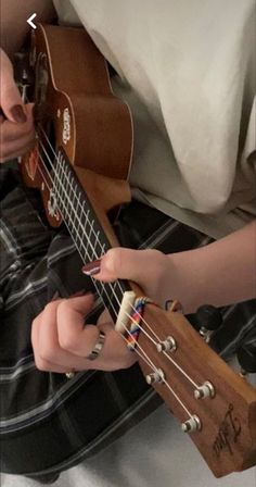 a person is playing an ukulele on the bed with their hands and fingers